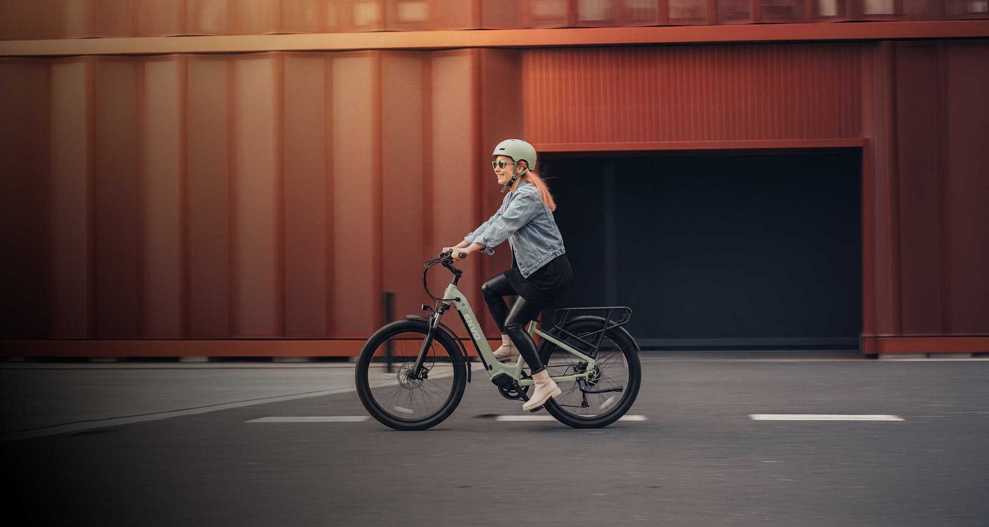 Woman riding ENVO electric bike along an open path on a sunny day